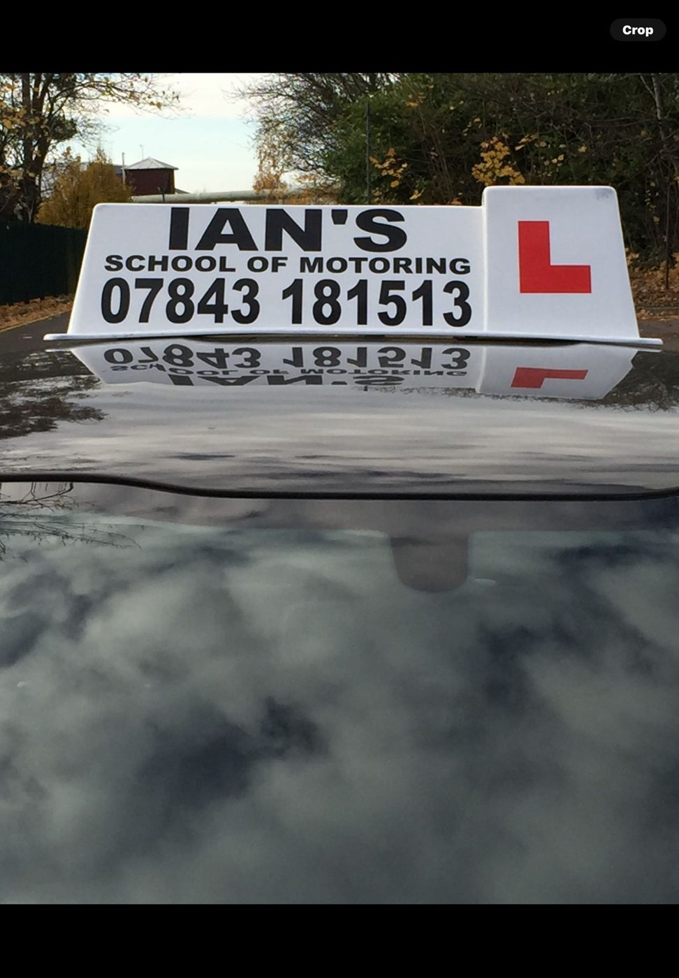 Close-up of the Ian's School of Motoring roof sign showing the 07843 181513 phone number