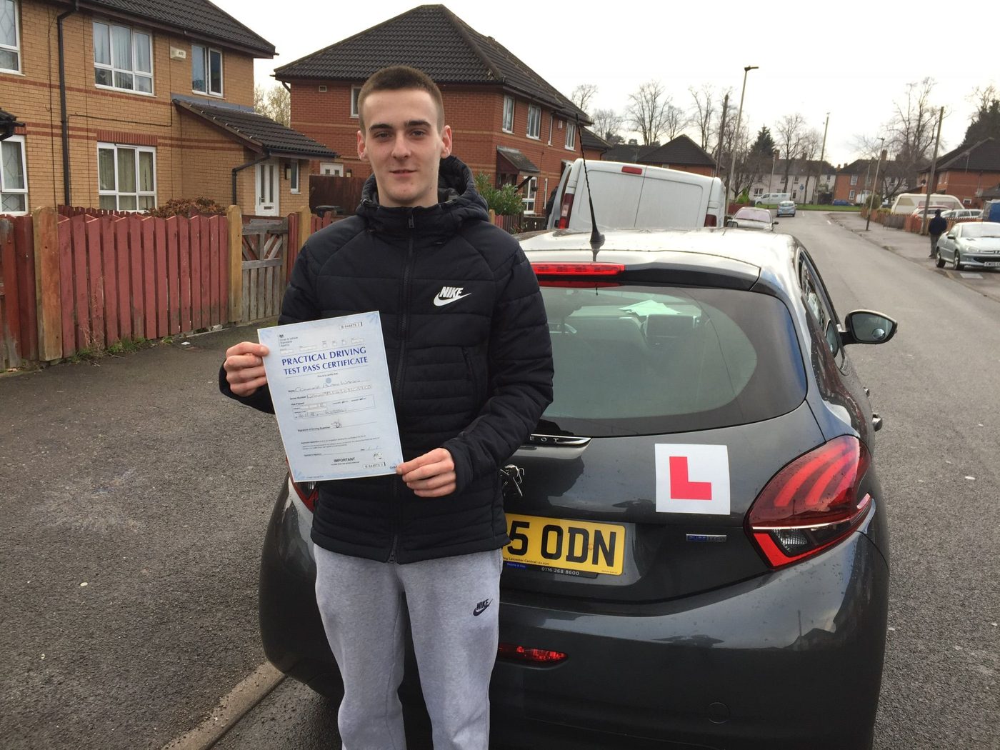 Learner celebrating his driving test pass beside Ian's School of Motoring car