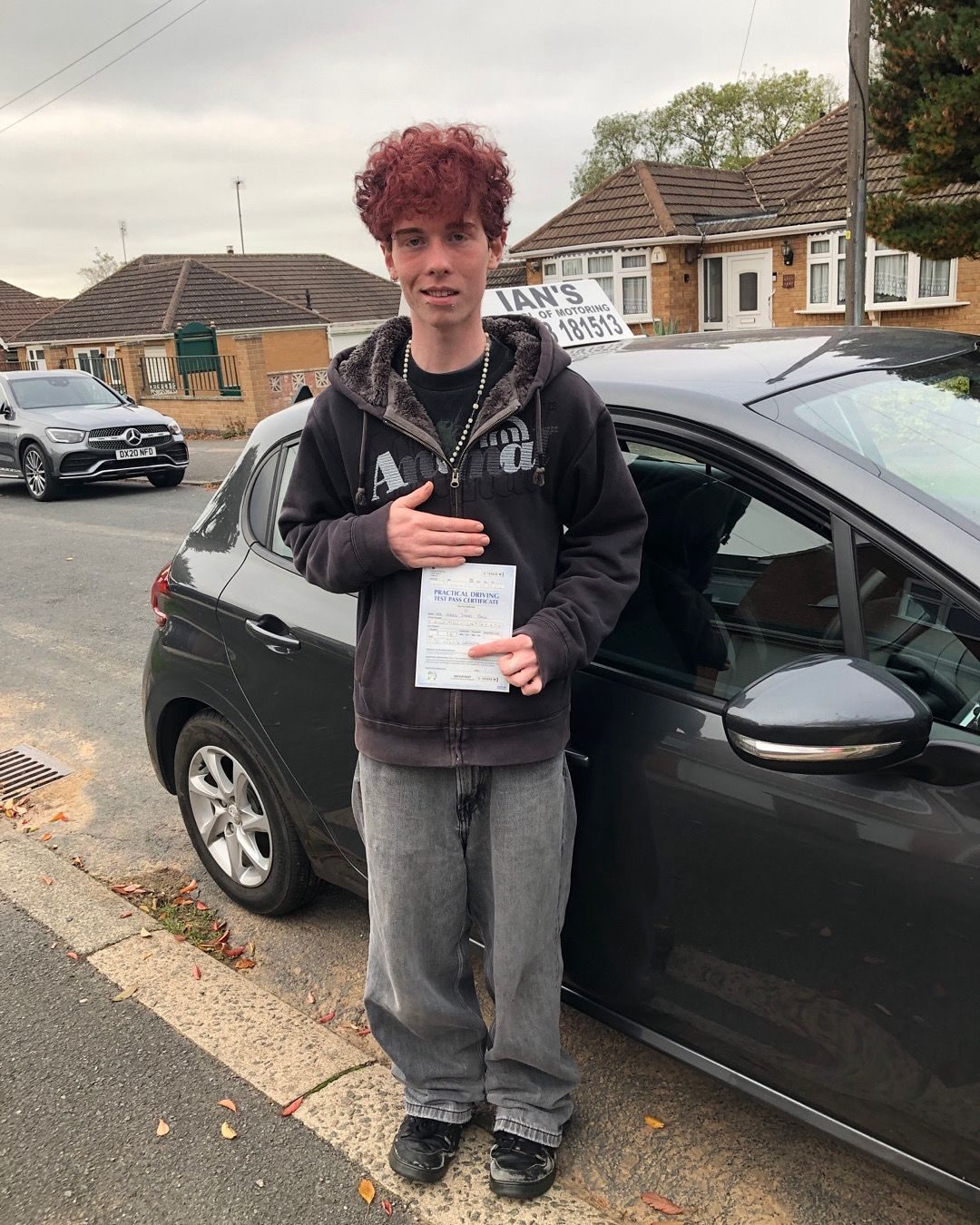 Young driver with his practical test pass certificate outside his home in Leicester