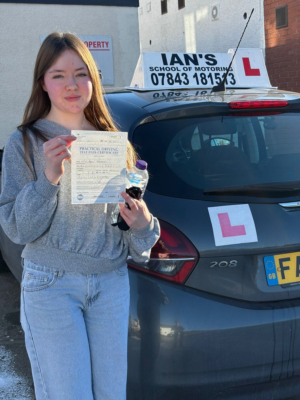 Learner holding her pass certificate beside Ian's School of Motoring tuition car