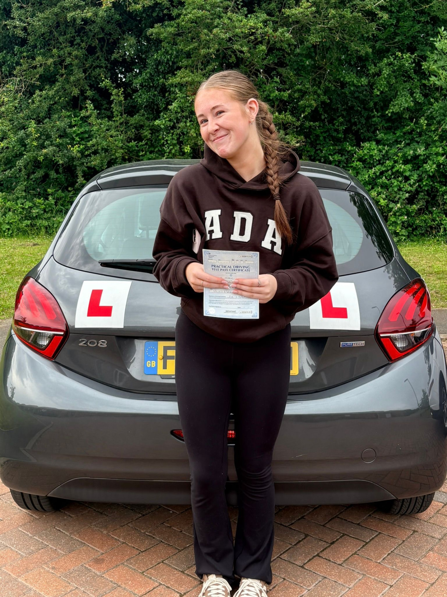 Learner celebrating a driving test pass with L plates on the car in Leicester