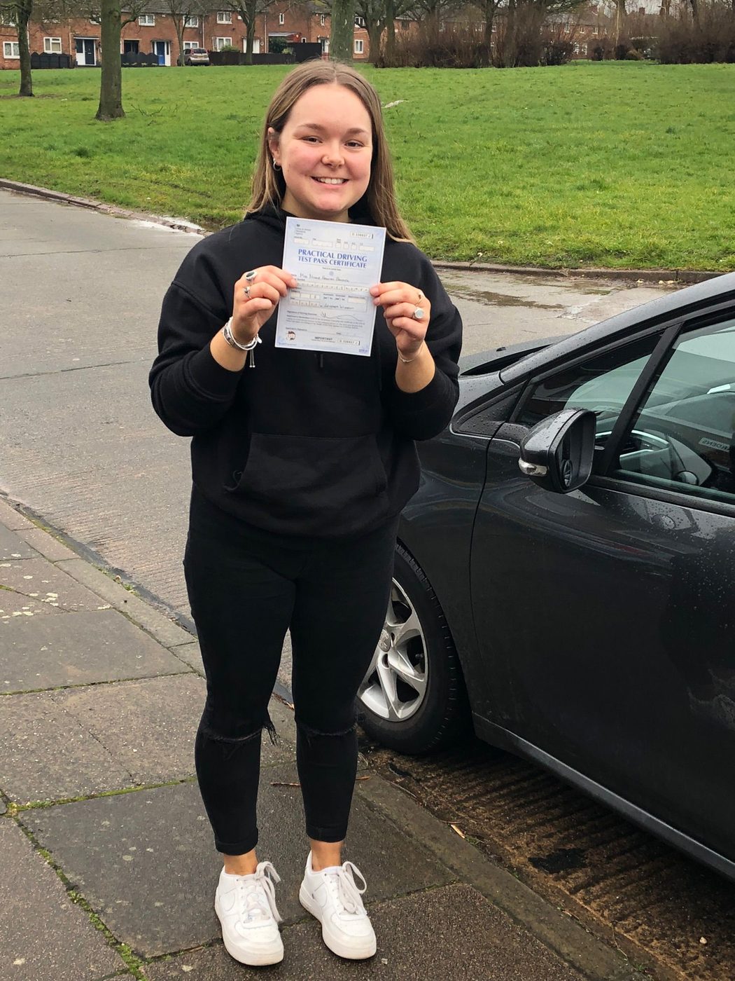 Learner holding her practical driving test pass certificate in Leicester