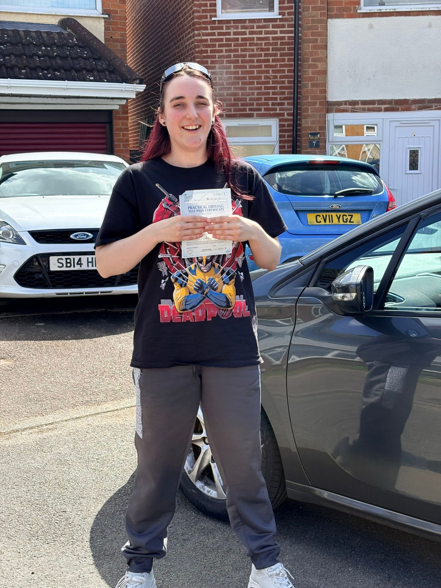 Learner holding their practical driving test pass certificate beside Ian's tuition car