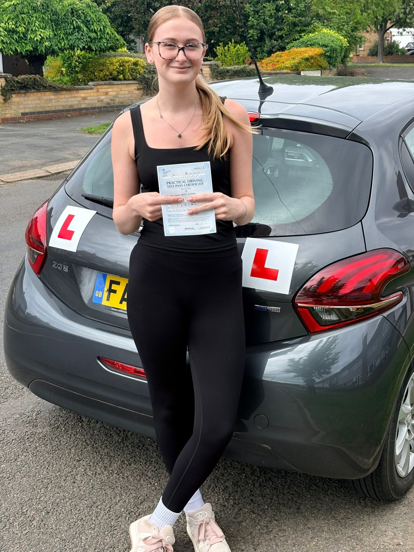 Learner holding a practical driving test pass certificate after lessons in Leicester